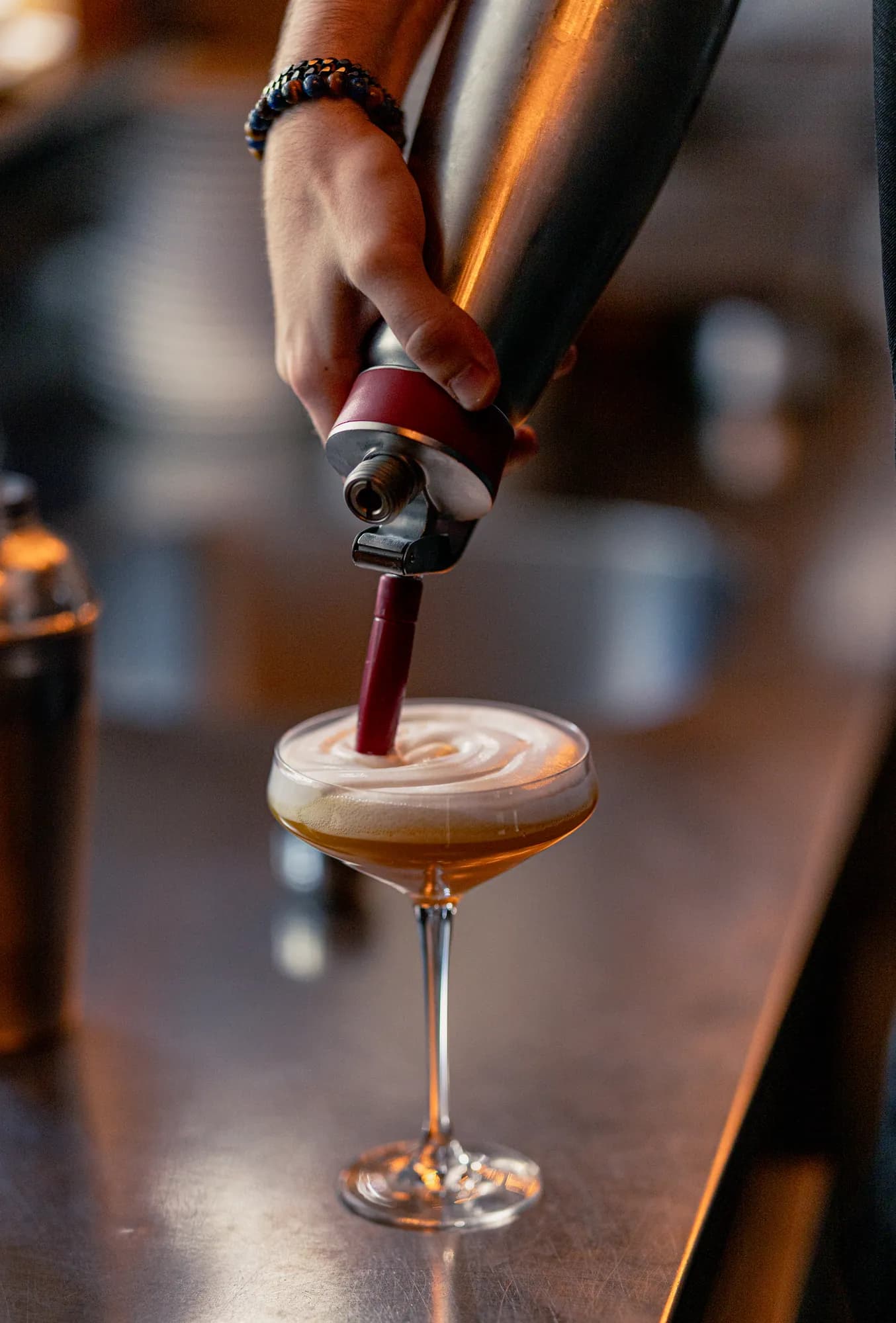Een cocktail wordt aan de bar afgemaakt met een schuimlaag