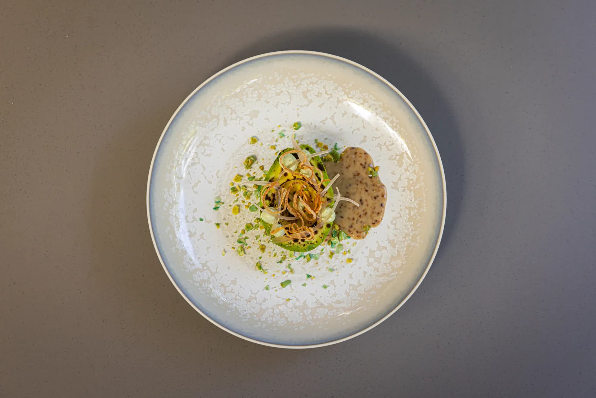 Gegrilde avocado met krokante ui en een romige saus op licht servies