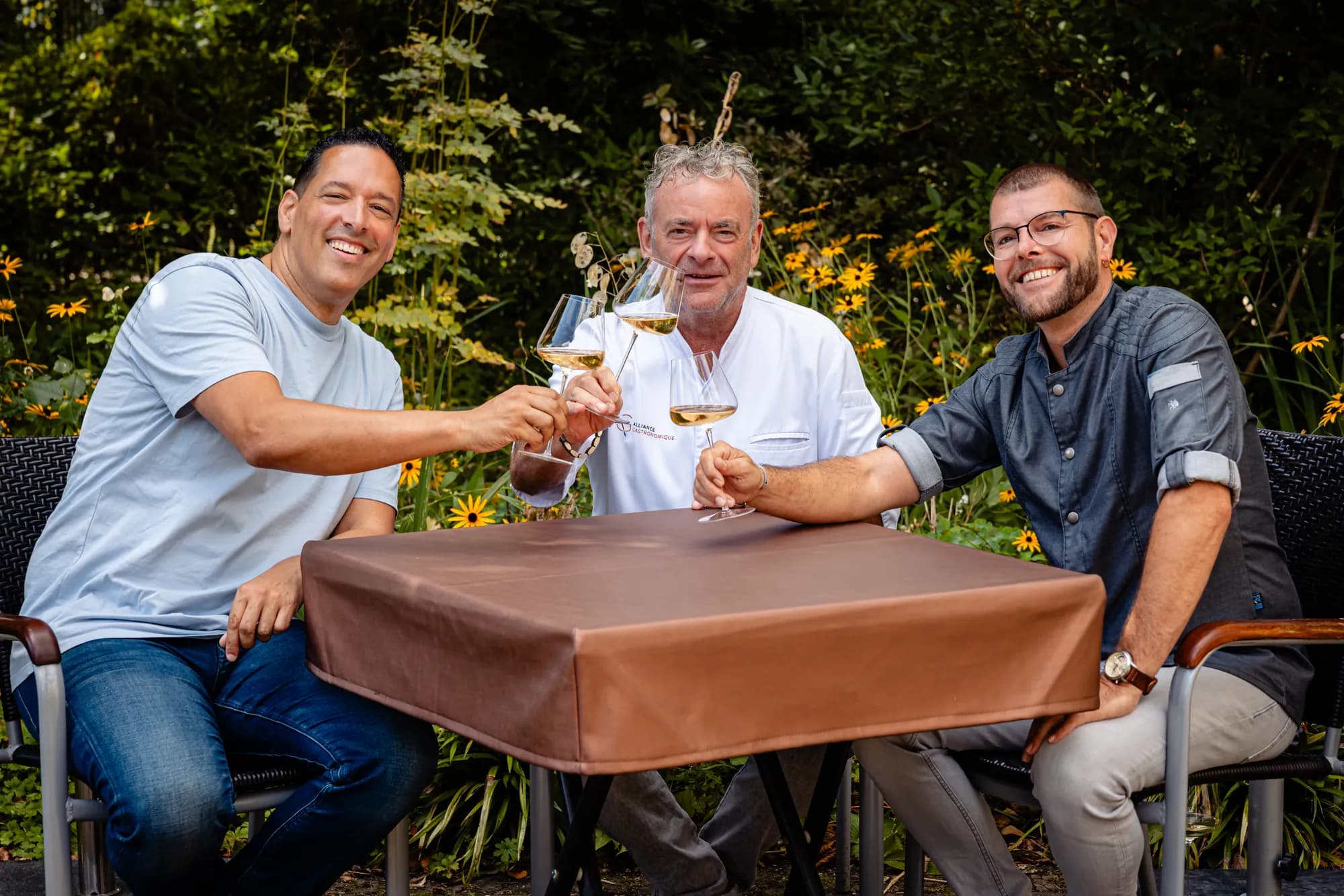 Proosten met witte wijn aan een tafel in de tuin, met chef Marcel van Zomeren