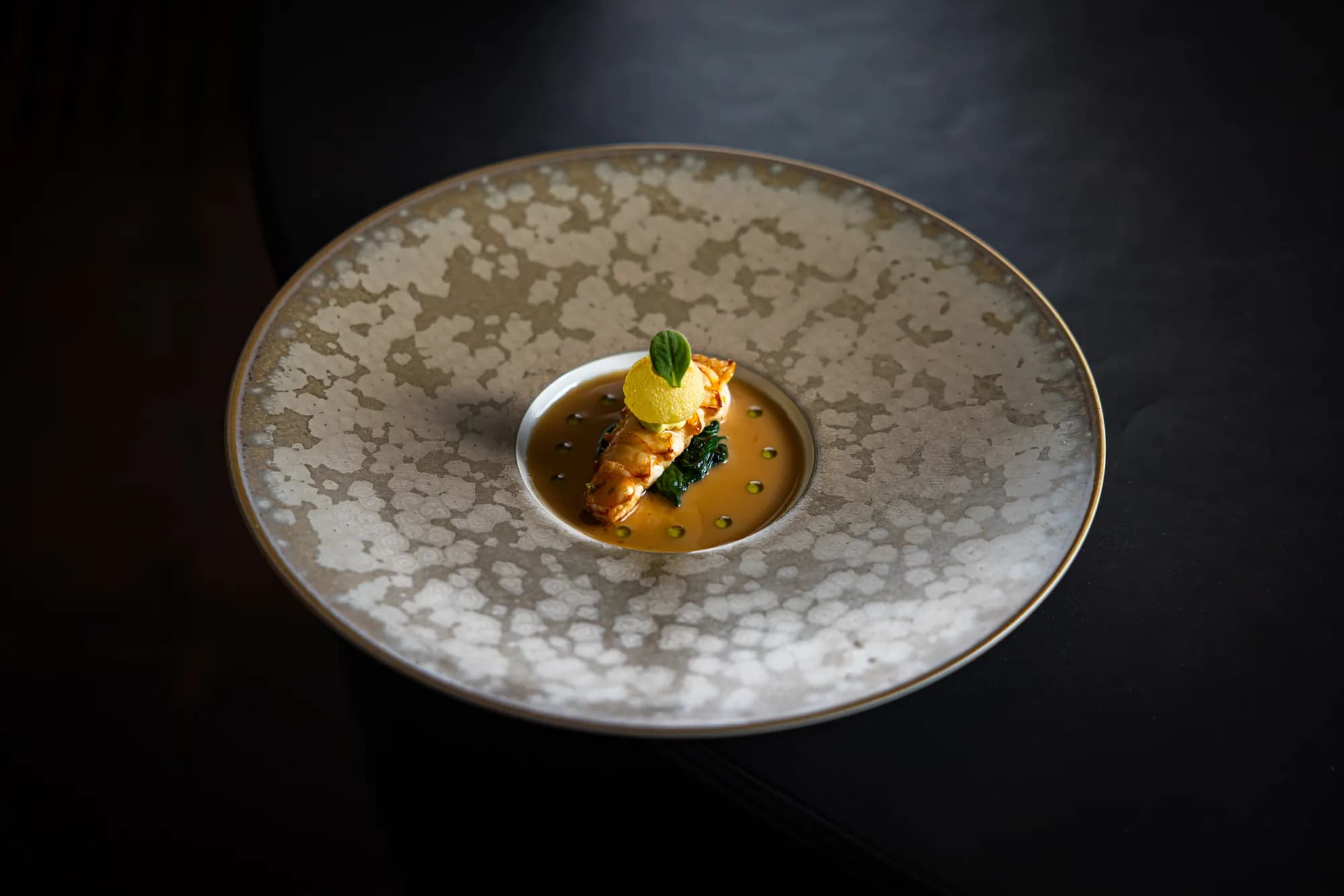Langoustine op spinazie in goudgele saus, schuin van boven gezien